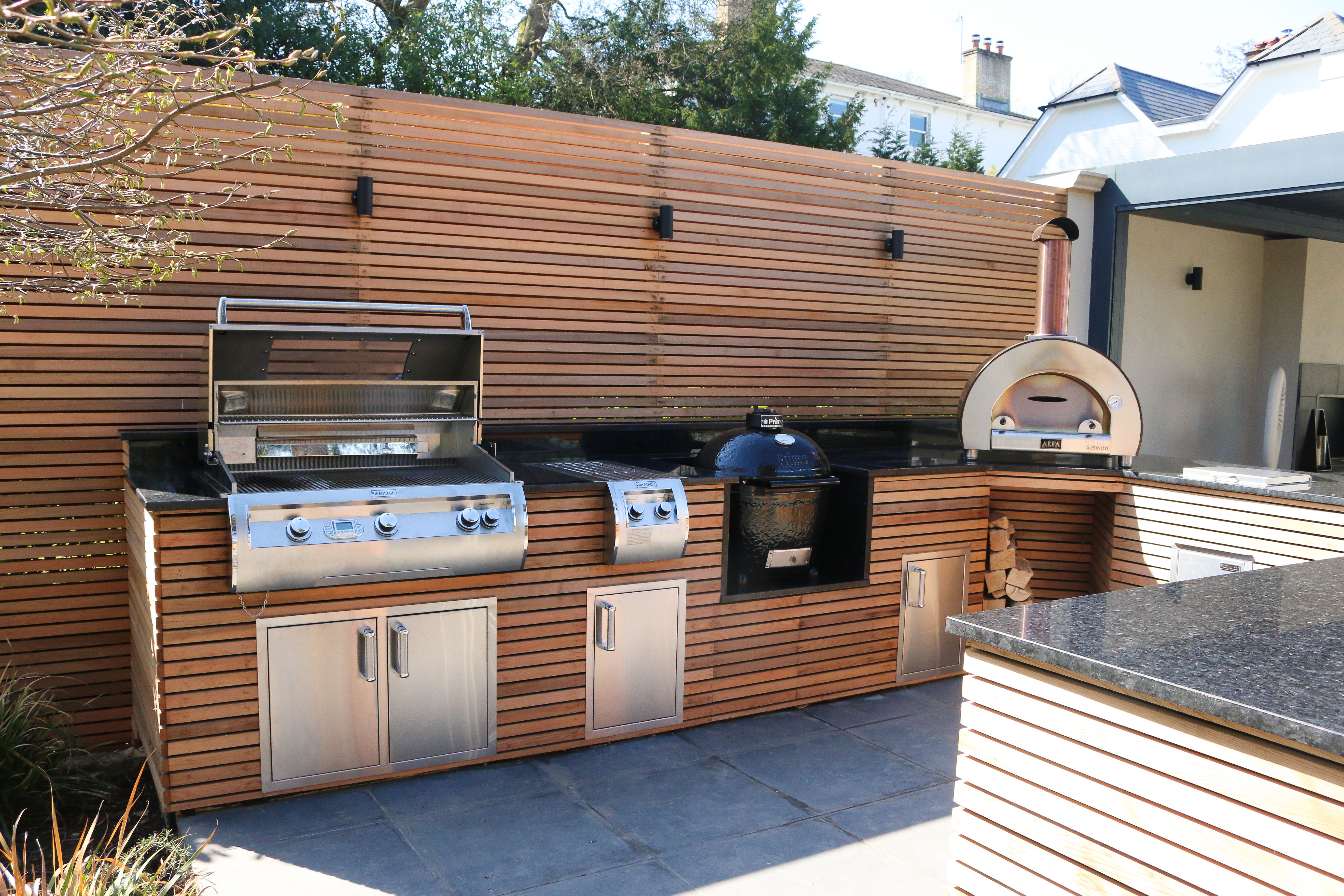 An outdoor kitchen featuring a Fire Magic BBQ grill and side burner.